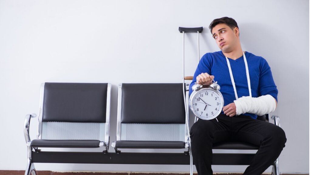 Rapaz com o braço machucado e muletas esperando para ser atendido, segurando um relógio