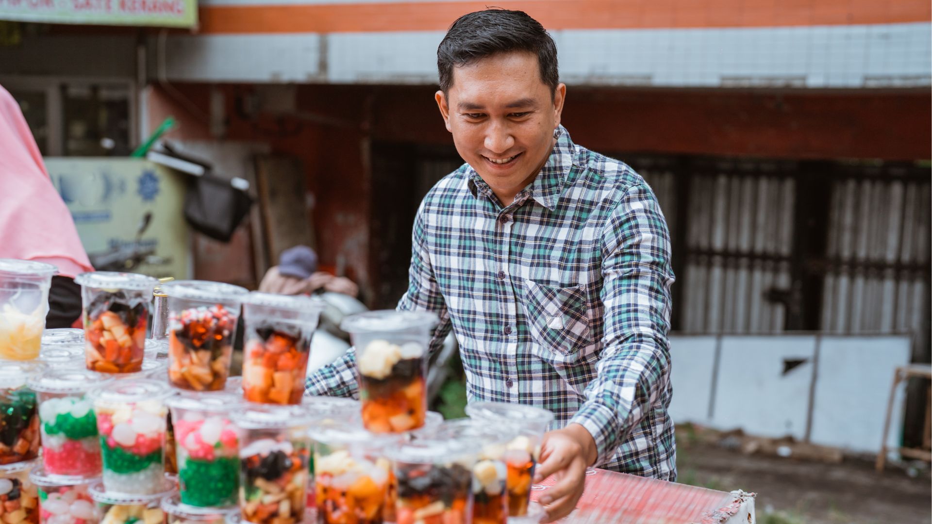 Homem vendendo salada de frutas e doces em potes na rua