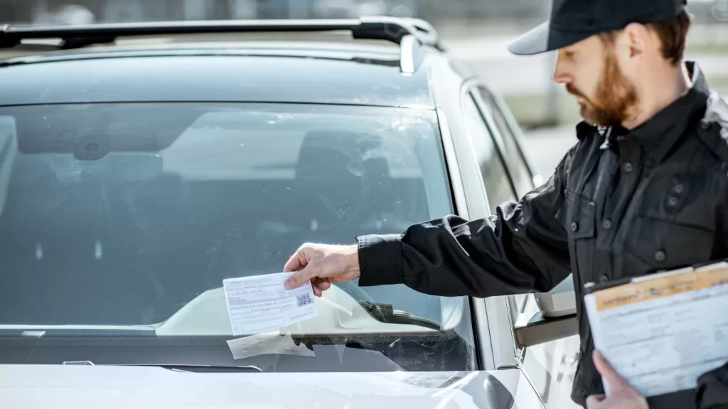 Guarda deixando multa de trânsito no parabrisas do carro